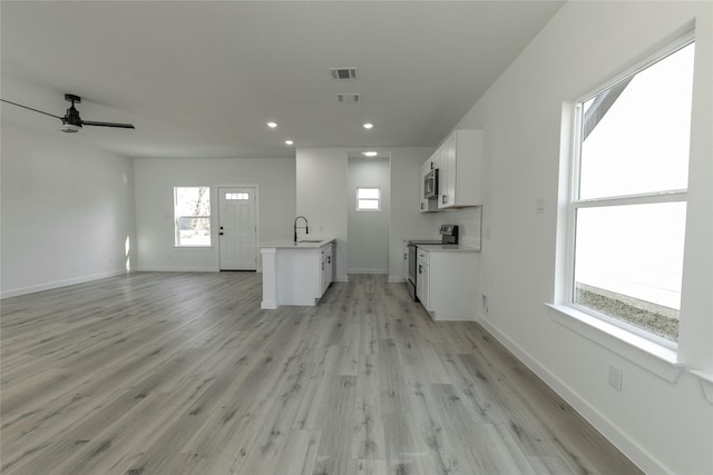 unfurnished living room with ceiling fan, sink, and light hardwood / wood-style flooring