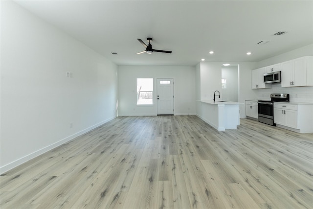 unfurnished living room featuring ceiling fan, light hardwood / wood-style flooring, and sink