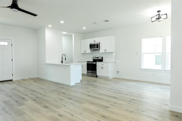 kitchen featuring kitchen peninsula, appliances with stainless steel finishes, white cabinets, light hardwood / wood-style flooring, and sink