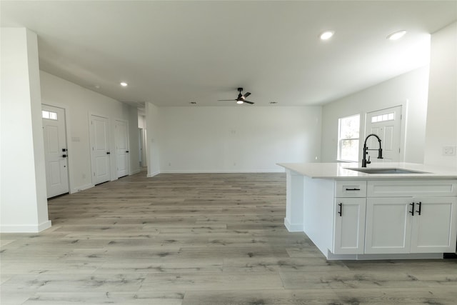 kitchen featuring ceiling fan, sink, and white cabinetry