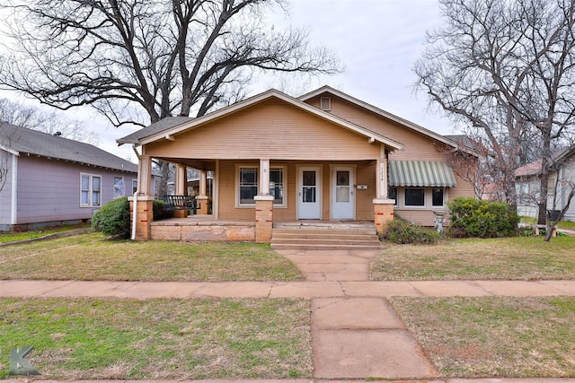 bungalow featuring covered porch and a front lawn