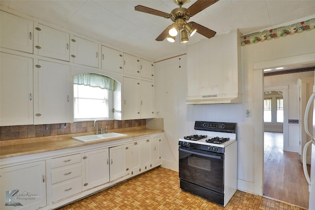 kitchen featuring white cabinetry, ceiling fan, decorative backsplash, gas range oven, and sink