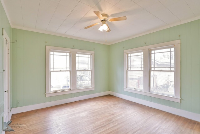 unfurnished room with light wood-type flooring, ceiling fan, a wealth of natural light, and ornamental molding