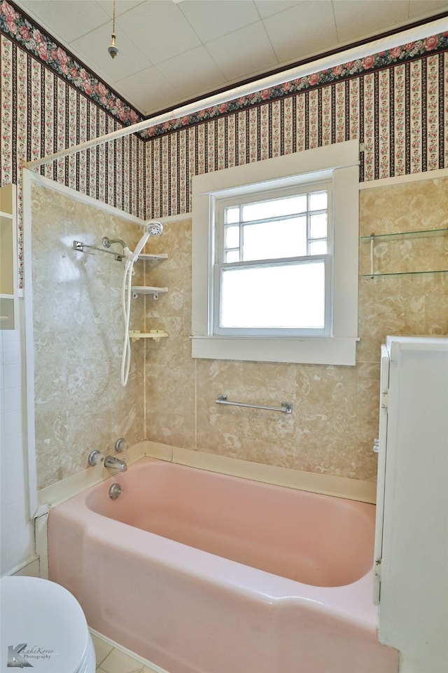 bathroom with toilet and tiled shower / bath