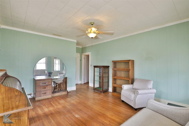 living area with ceiling fan, crown molding, and light hardwood / wood-style floors