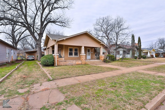 bungalow-style home with a front yard, covered porch, and a carport