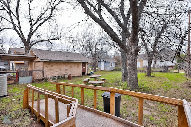 view of yard with central air condition unit, a deck, and a storage shed