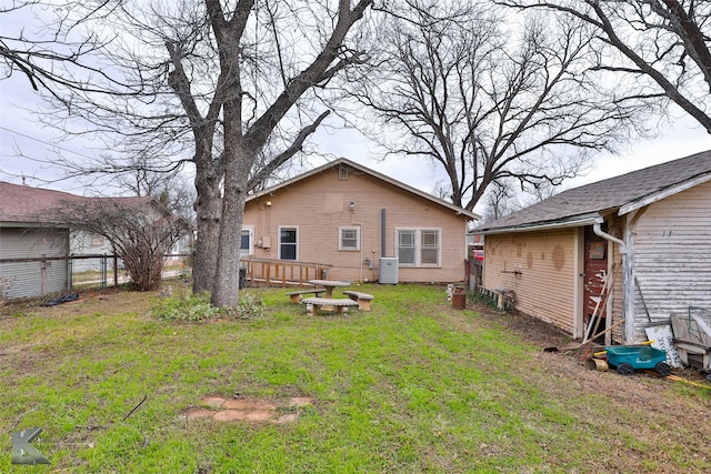 rear view of house featuring central air condition unit and a lawn