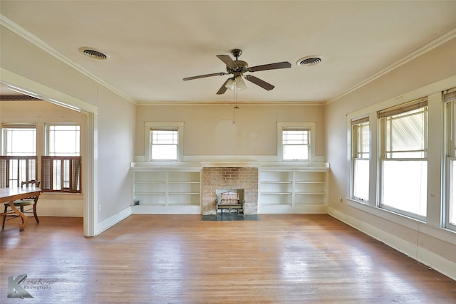 unfurnished living room featuring crown molding, plenty of natural light, and built in shelves