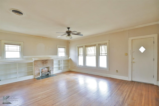 unfurnished living room featuring ceiling fan, crown molding, light hardwood / wood-style floors, and built in shelves