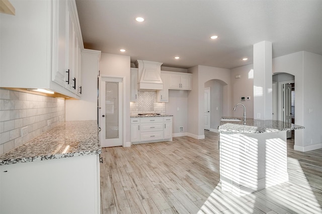 300 Ben Thomas St, Burleson, TX 76028 - kitchen with custom exhaust hood, arched walkways, decorative backsplash, white cabinets, and recessed lighting