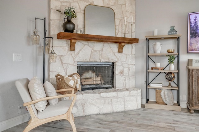 interior details with a stone fireplace, baseboards, and wood finished floors