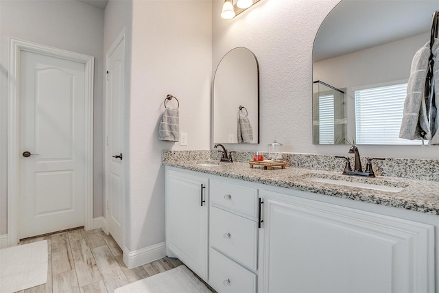 bathroom featuring double vanity, baseboards, a sink, and wood finished floors