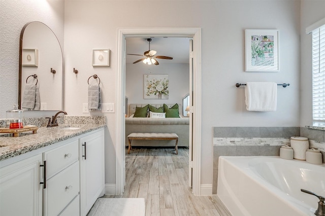 full bathroom with a ceiling fan, connected bathroom, vanity, wood finished floors, and a bath