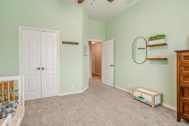 unfurnished bedroom featuring light carpet, ceiling fan, a closet, and baseboards