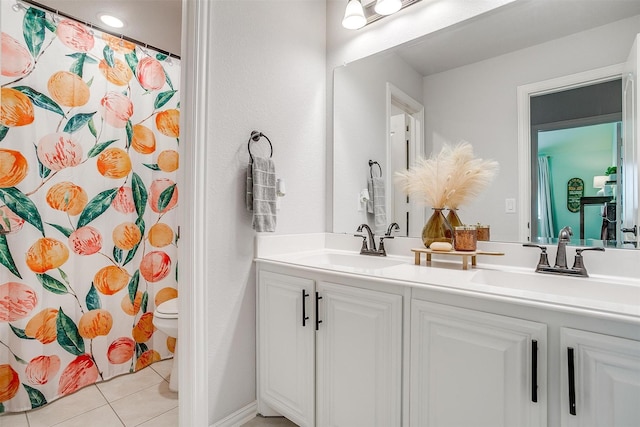 bathroom with double vanity, tile patterned flooring, a sink, and toilet