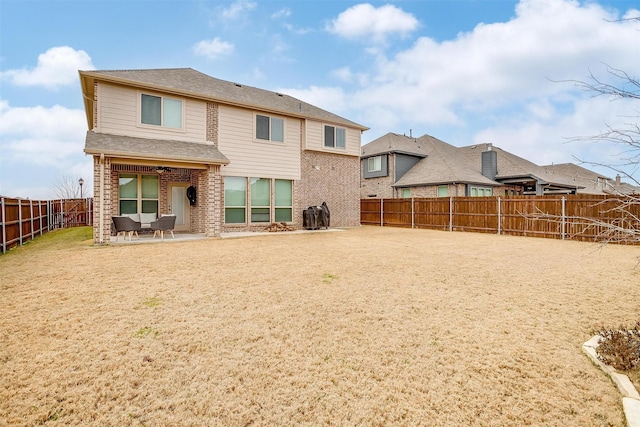 rear view of house with a patio, brick siding, and a fenced backyard