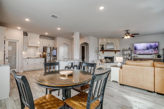 300 Ben Thomas St, Burleson, TX 76028 - dining room featuring a ceiling fan, light wood-style floors, a fireplace, arched walkways, and recessed lighting