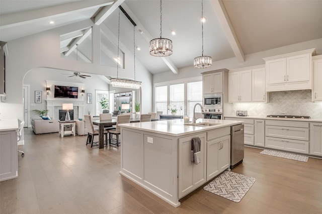 kitchen with an island with sink, appliances with stainless steel finishes, decorative light fixtures, white cabinets, and sink