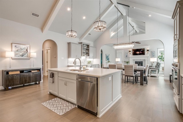 kitchen with stainless steel appliances, a kitchen island with sink, high vaulted ceiling, pendant lighting, and sink