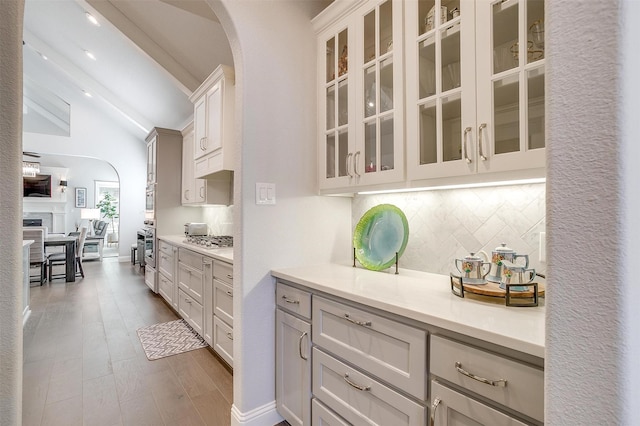 kitchen with lofted ceiling, dark hardwood / wood-style floors, decorative backsplash, white cabinetry, and appliances with stainless steel finishes