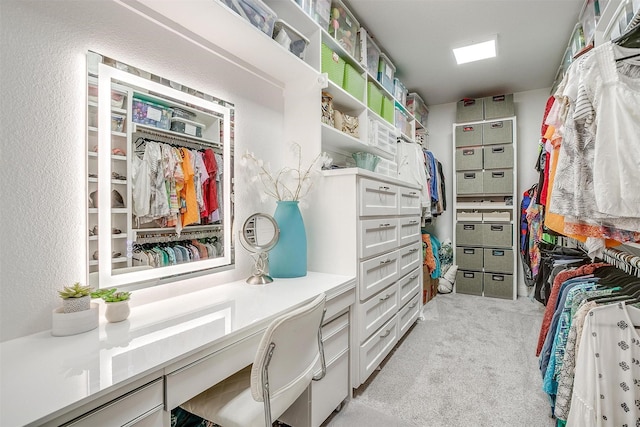 spacious closet featuring built in desk and light colored carpet