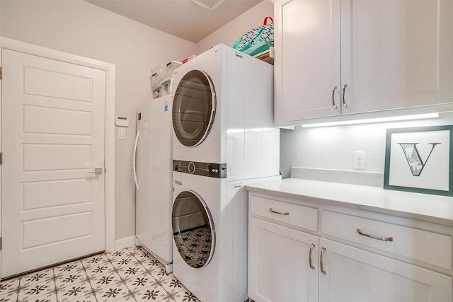 clothes washing area with stacked washing maching and dryer and cabinets