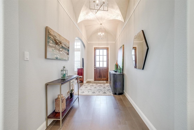 entrance foyer with wood-type flooring, vaulted ceiling, and an inviting chandelier