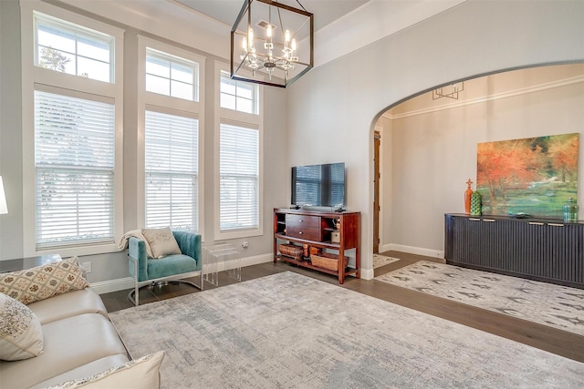 sitting room with a towering ceiling, plenty of natural light, dark hardwood / wood-style floors, and a chandelier