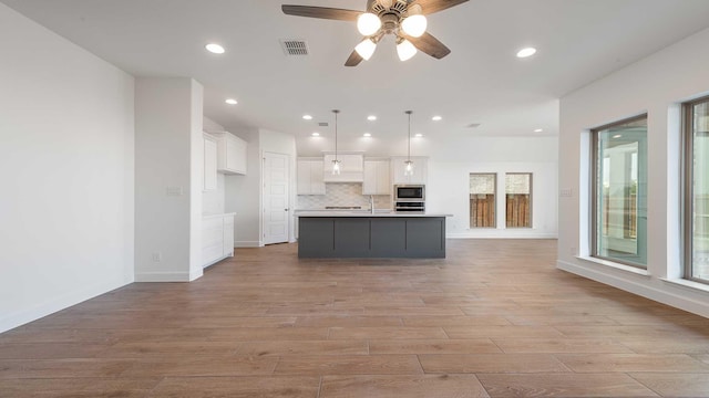 4601 Timberdrift St, Midlothian, TX 76065 - kitchen with stainless steel appliances, white cabinets, light wood finished floors, open floor plan, and recessed lighting
