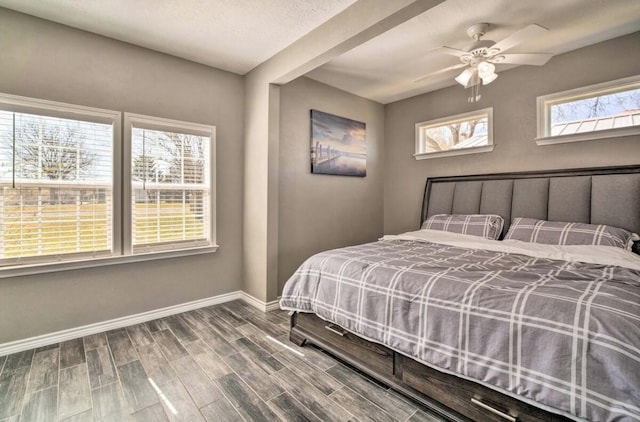 bedroom with ceiling fan, wood-type flooring, and a textured ceiling