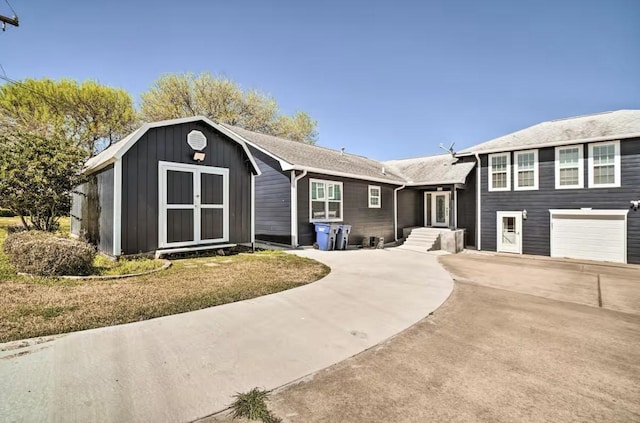 view of front of house with a garage, a front yard, and a shed