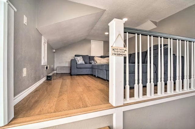 staircase with a textured ceiling, lofted ceiling, and hardwood / wood-style floors