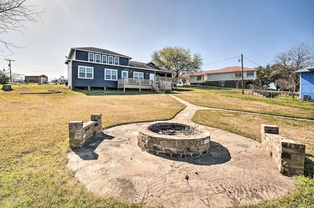 back of property featuring a deck, an outdoor fire pit, and a yard