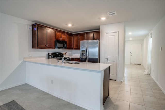 kitchen with range, sink, stainless steel fridge, kitchen peninsula, and light tile patterned floors