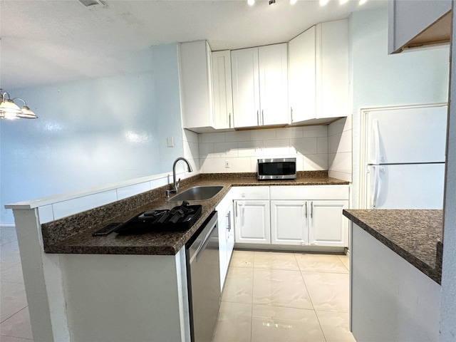 kitchen featuring white cabinets, appliances with stainless steel finishes, tasteful backsplash, sink, and kitchen peninsula