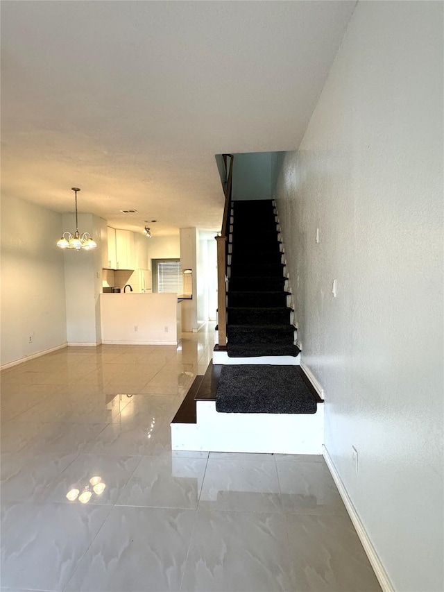 staircase with a notable chandelier