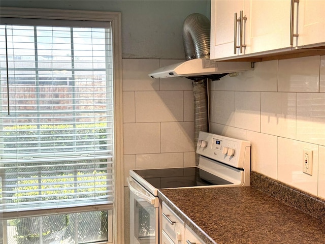 kitchen with electric range, white cabinets, and exhaust hood