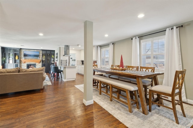 dining space with dark wood-type flooring, plenty of natural light, and a fireplace