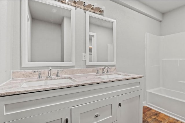 bathroom featuring wood-type flooring, washtub / shower combination, and vanity