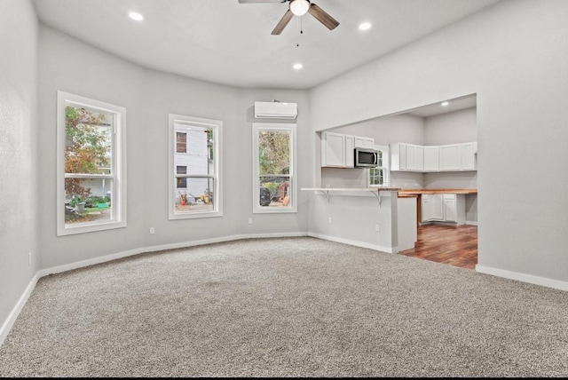 unfurnished living room featuring ceiling fan, carpet flooring, and a wall mounted air conditioner