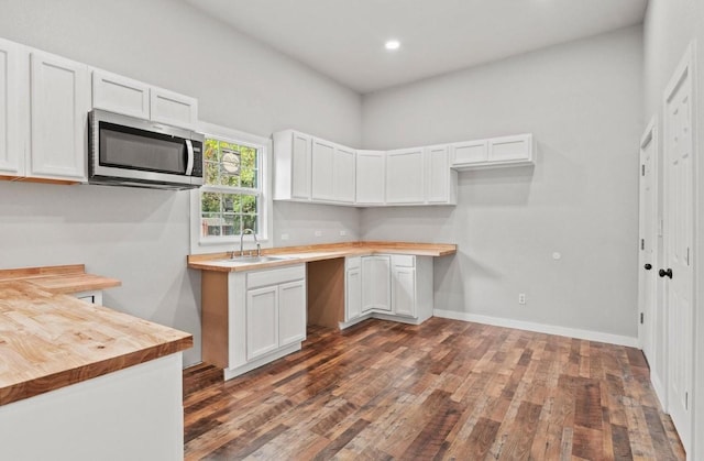 kitchen with a high ceiling, white cabinetry, butcher block counters, sink, and dark hardwood / wood-style floors