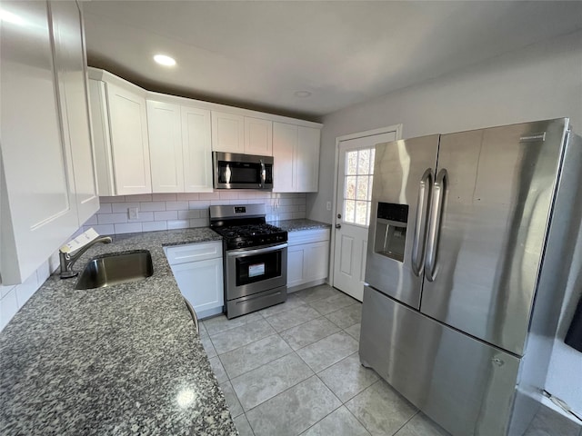 kitchen with stone counters, appliances with stainless steel finishes, white cabinets, sink, and backsplash