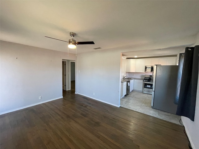 unfurnished living room featuring sink, light wood-type flooring, and ceiling fan