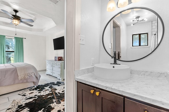 bathroom with ceiling fan, a raised ceiling, and vanity