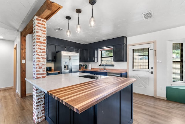 kitchen with decorative light fixtures, light hardwood / wood-style flooring, stainless steel appliances, and wooden counters