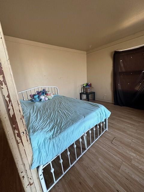 bedroom with hardwood / wood-style flooring and ornamental molding