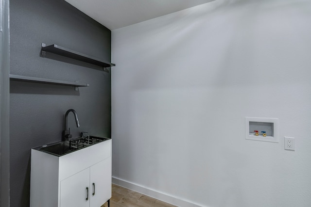 clothes washing area with cabinets, washer hookup, light hardwood / wood-style flooring, and sink