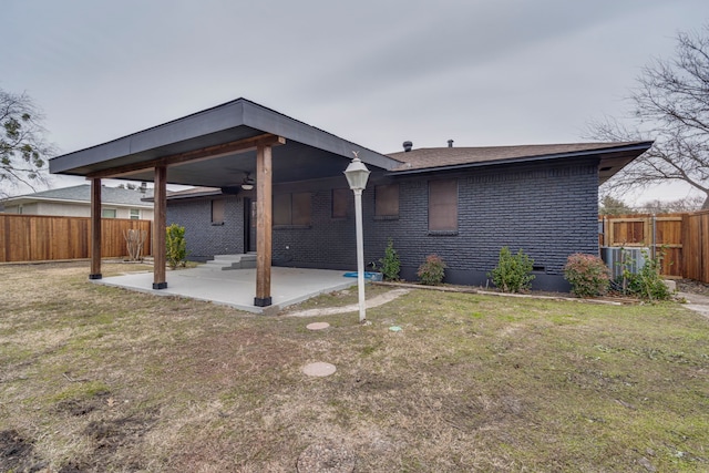 back of property with ceiling fan, a yard, and a patio