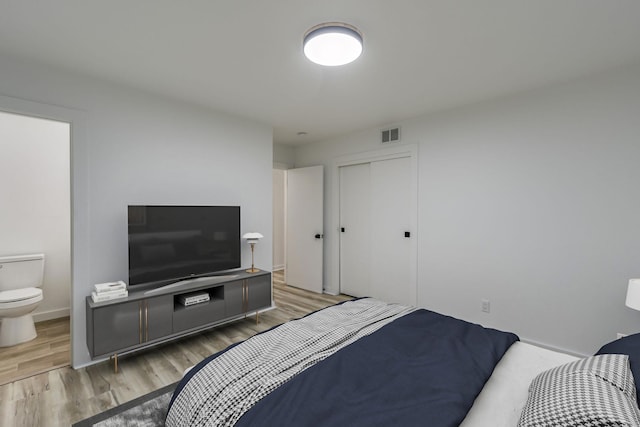 bedroom with a closet, light hardwood / wood-style floors, and ensuite bath